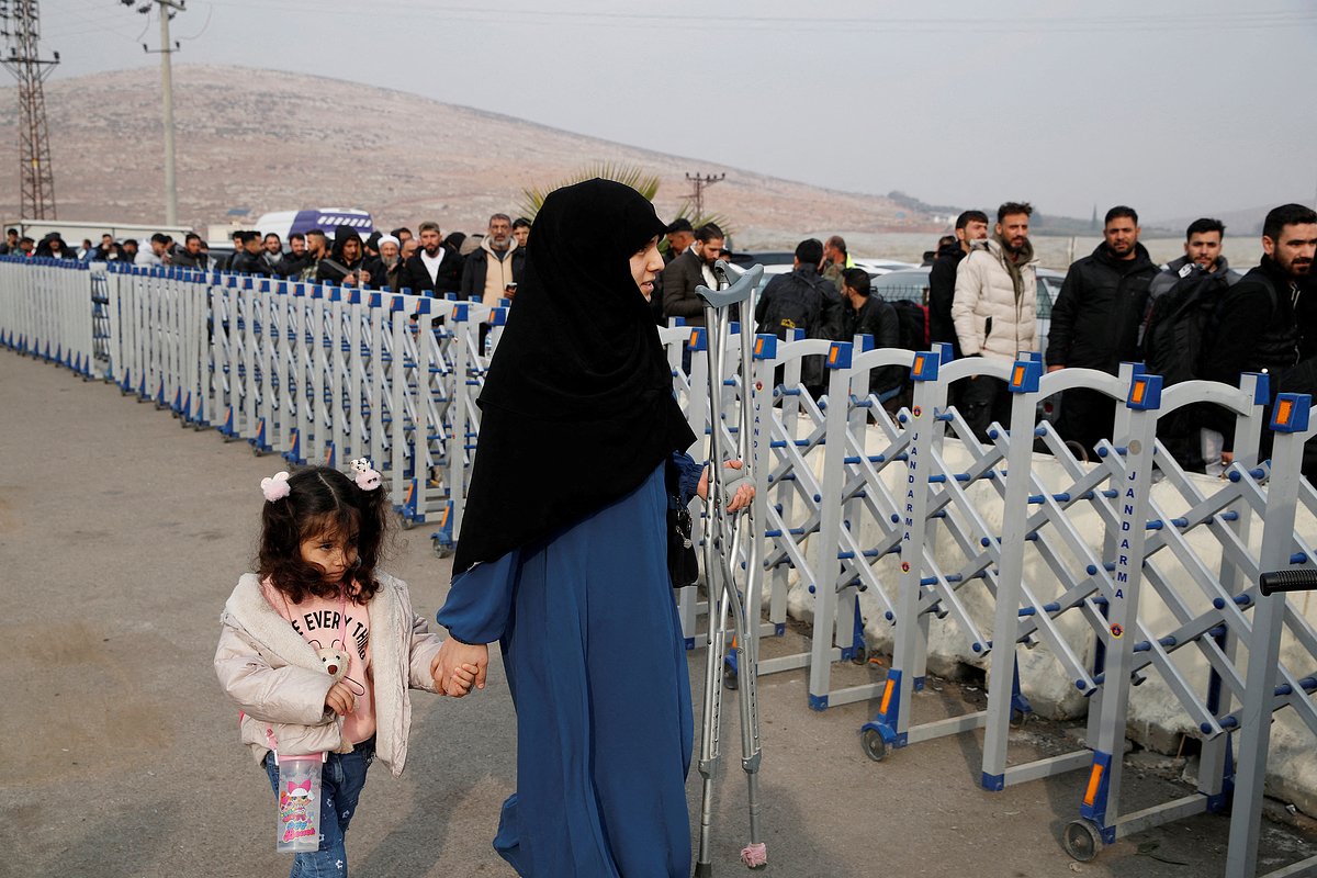 A woman walks past security barriers as Syrian migrants wait in line to cross into Syria, after Syrian rebels ousted President Bashar al-Assad, at Cilvegozu border gate in Hatay province, Turkey, December 11, 2024. REUTERS/Dilara Senkaya
