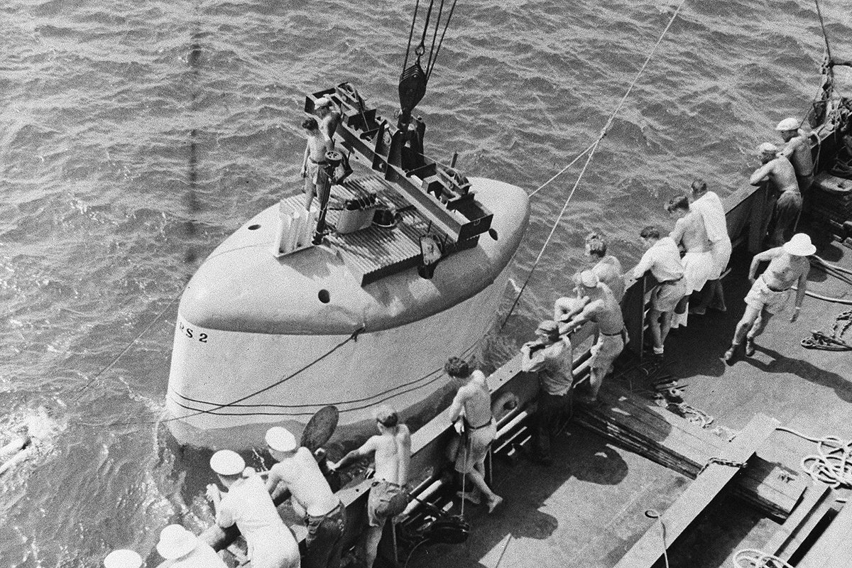 The bathyscape, in which Professor Auguste Piccard hopes to dive two and a half miles into the ocean, is lowered into water off African coast Oct. 31, 1948, as crewmen of mother ship. S. S. Scaldis looks on. The deep sea expedition is now off Cape Verde Islands. (AP Photo.Paris Soir)