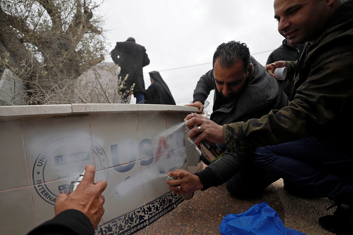 Палестинцы закрашивают логотип USAID в знак протеста против мирного плана президента США Дональда Трампа для Ближнего Востока, Рамалла, 4 февраля 2020 года