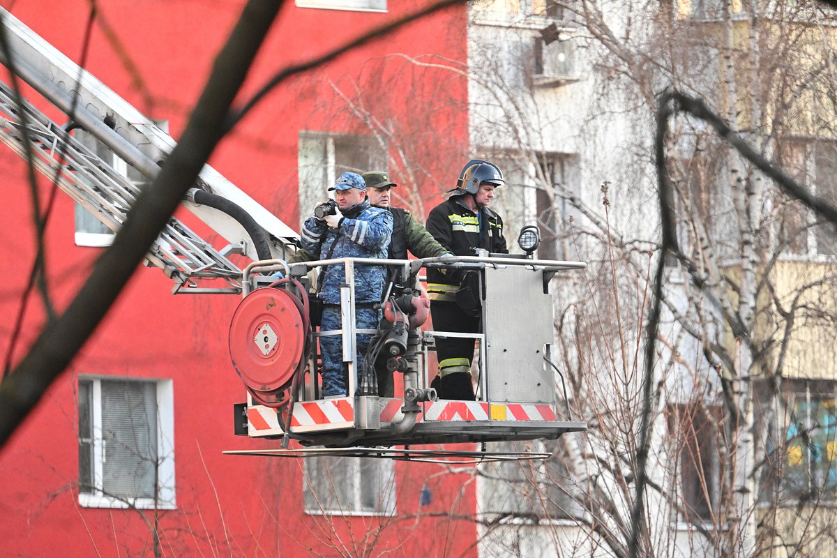 Сотрудники спецслужб у поврежденного из-за падения обломков БПЛА в Москве. 