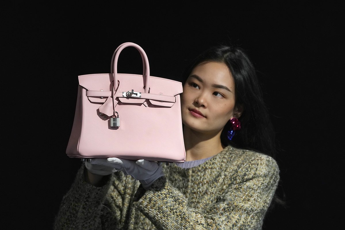 Сотрудница британского дома Bonhams демонстрирует сумку Rose Sakura Swift Leather Birkin 25 в аукционном зале в Лондоне. Оценочная стоимость аксессуара составляет 18–22 тысячи фунтов стерлингов (22,8–27,9 тысячи долларов США), он был выставлен на торги 28 февраля 2024 года