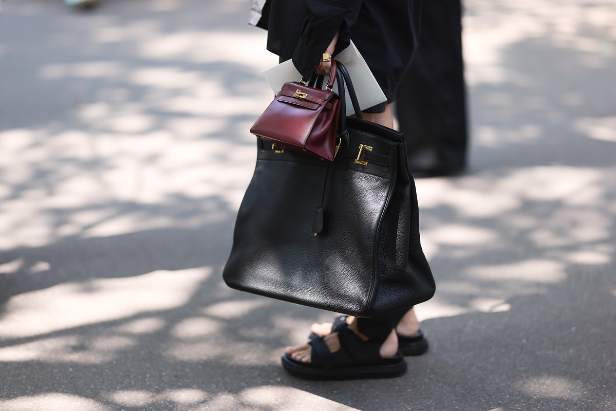 Гостья Недели моды с черной кожаной сумкой Hermes Birkin 50 и мини-сумкой Hermes Kelly бордового цвета