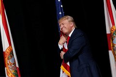 Трамп обнимает американский флаг в 2016 году.