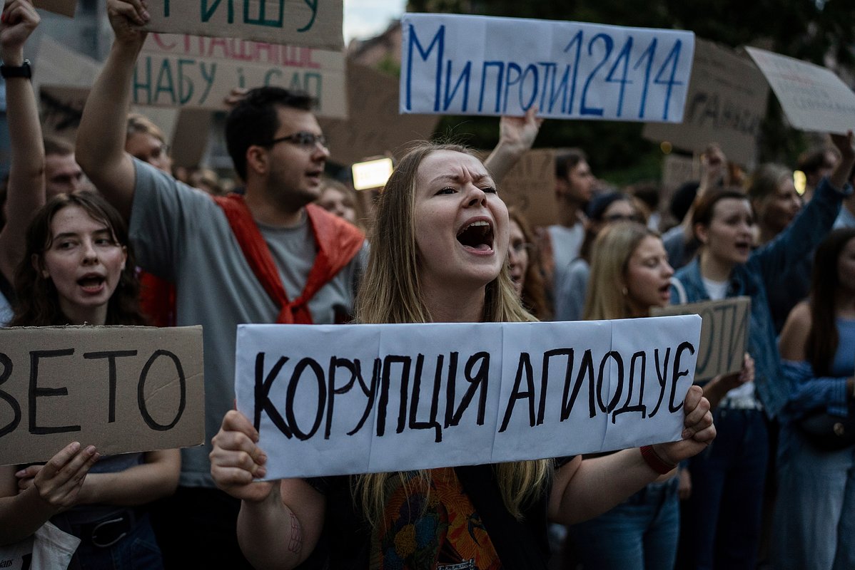 Женщина с плакатом «Коррупция аплодирует» на акции протеста из-за закона, направленного против антикоррупционных учреждений, Киев, 22 июля 2025 года.