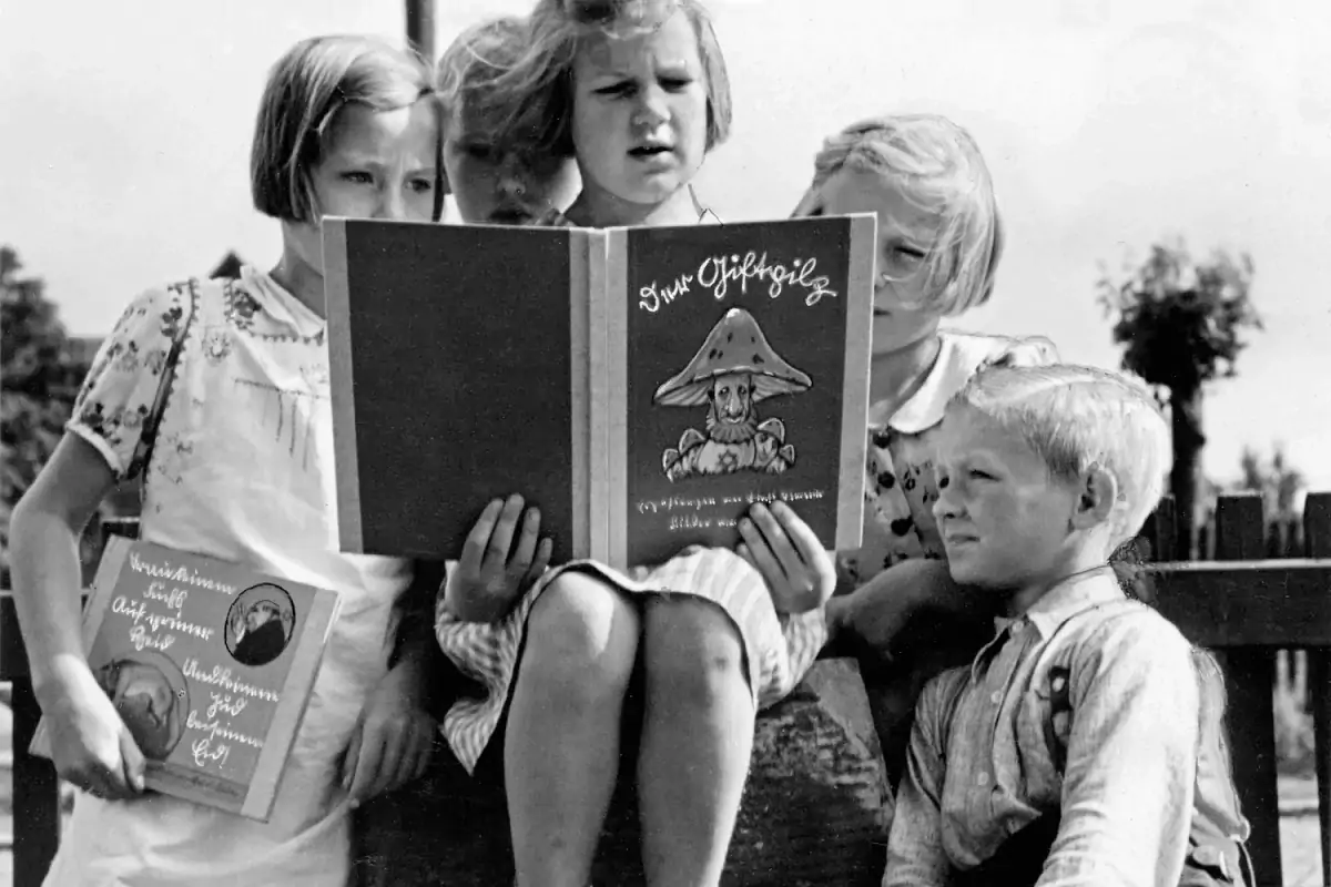 Немецкие дети читают антиеврейскую пропагандистскую книгу «Поганка». Девочка слева держит книгу с подобным содержанием, название которой переводится с немецкого как «Не верь лисе». Приблизительно 1938 год