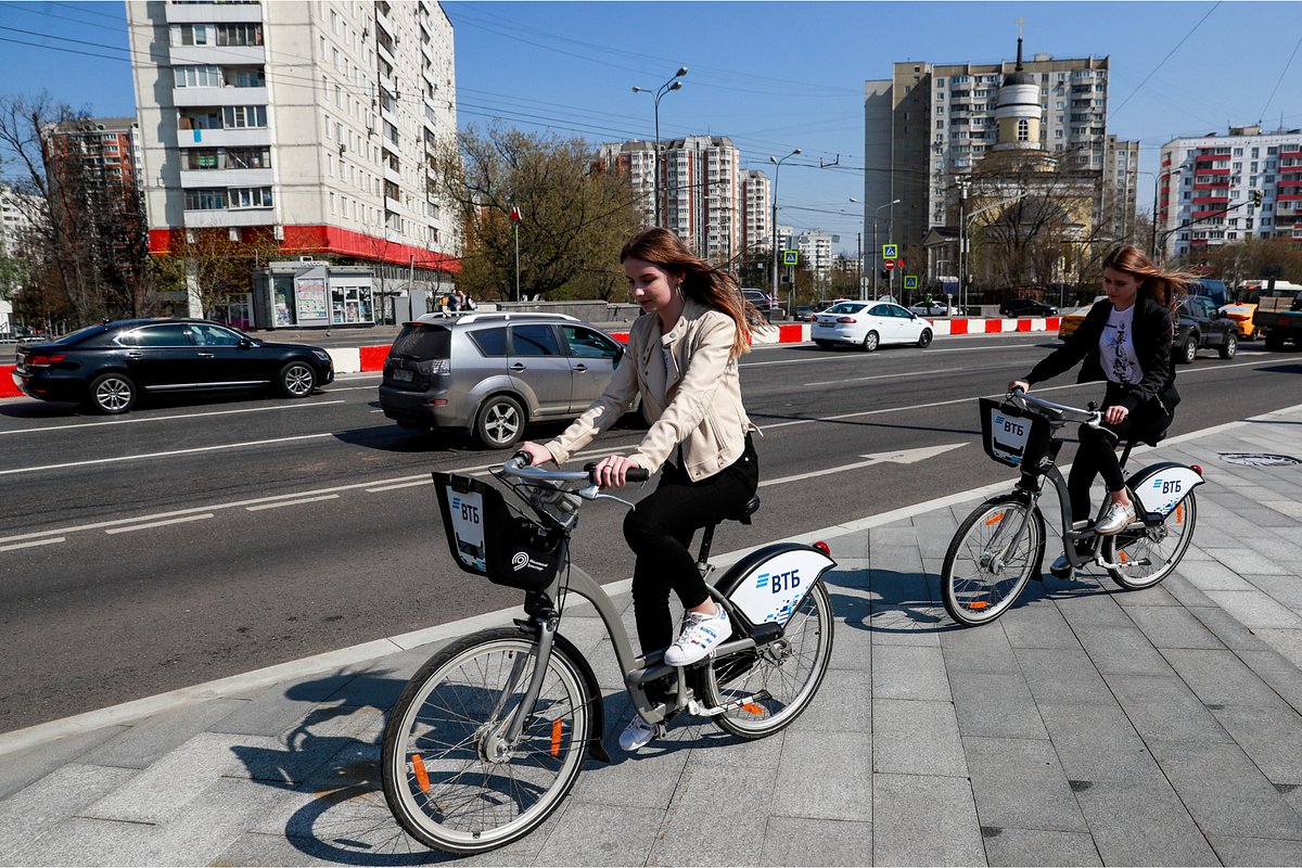 Россия. Москва. Девушки катаются на велосипедах у пункта проката велосипедов у станции метрополитена