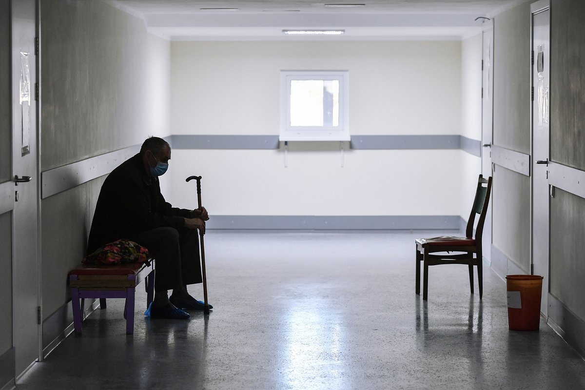 Пациент в медицинской маске ожидает приема врача в городской поликлинике