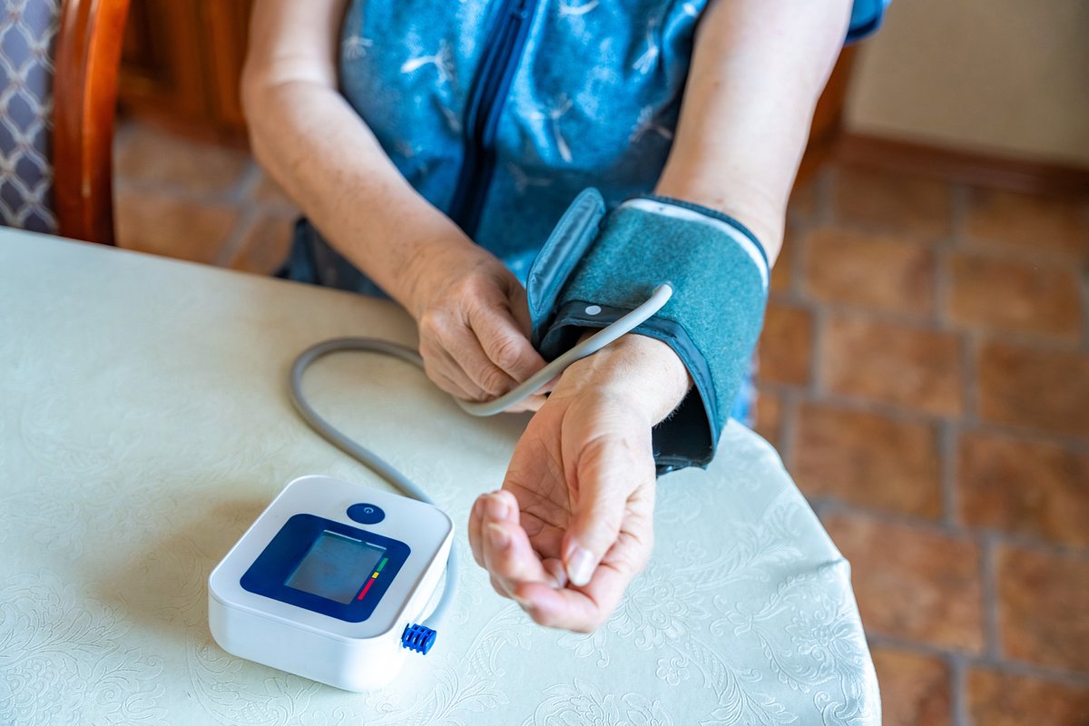 Senior woman start to check blood pressure level at home, older female suffering from high blood pressure sitting and using a pulsometer, tonometer.