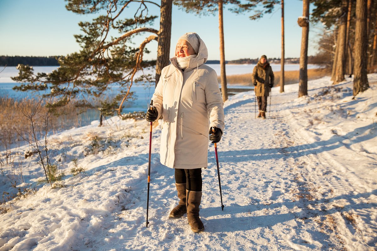 Winter sport - nordic walking. Senior woman and man hiking in cold forest. Active people outdoors.