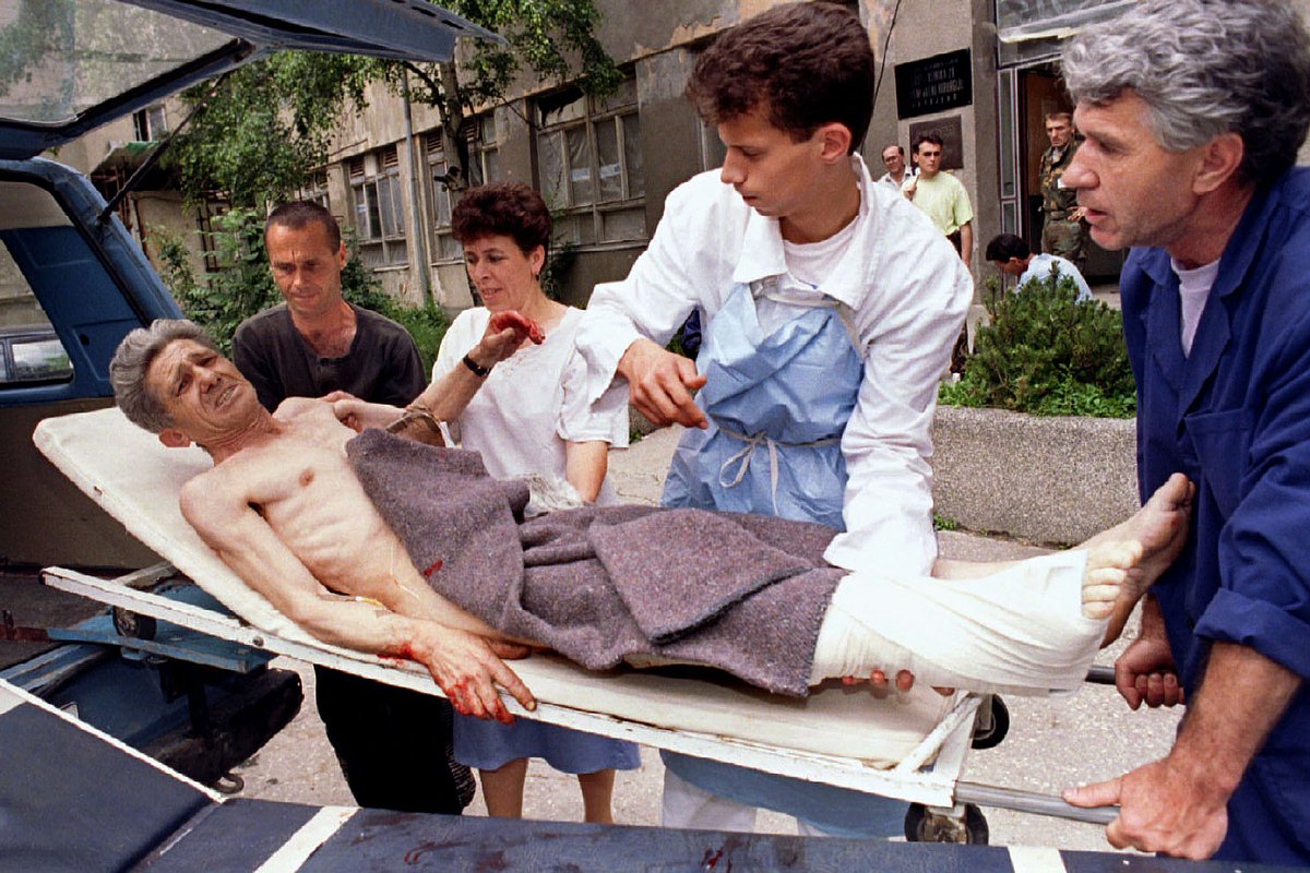 Медицинский персонал больницы Кошево выносит из машины скорой помощи жителя Сараево, раненного минометным обстрелом, 4 июля 1995 года