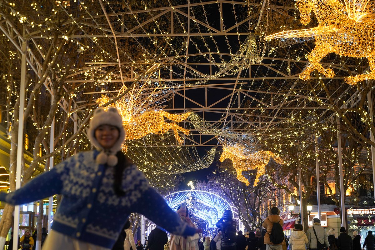 Туристы прогуливаются под светящимися инсталляциями в форме лошадей на Центральной улице Харбина 22 декабря 2025 года