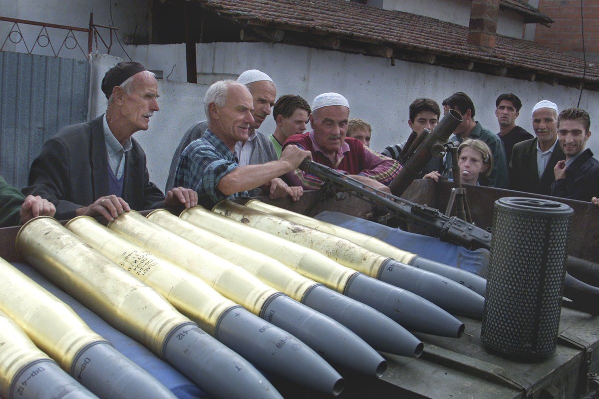 Пожилые албанские мужчины смотрят на пулемет и артиллерийские снаряды, перевозимые на грузовике через деревню Радуса, оплот Армии национального освобождения (АНО), к пункту сбора оружия. 7 сентября 2001 года