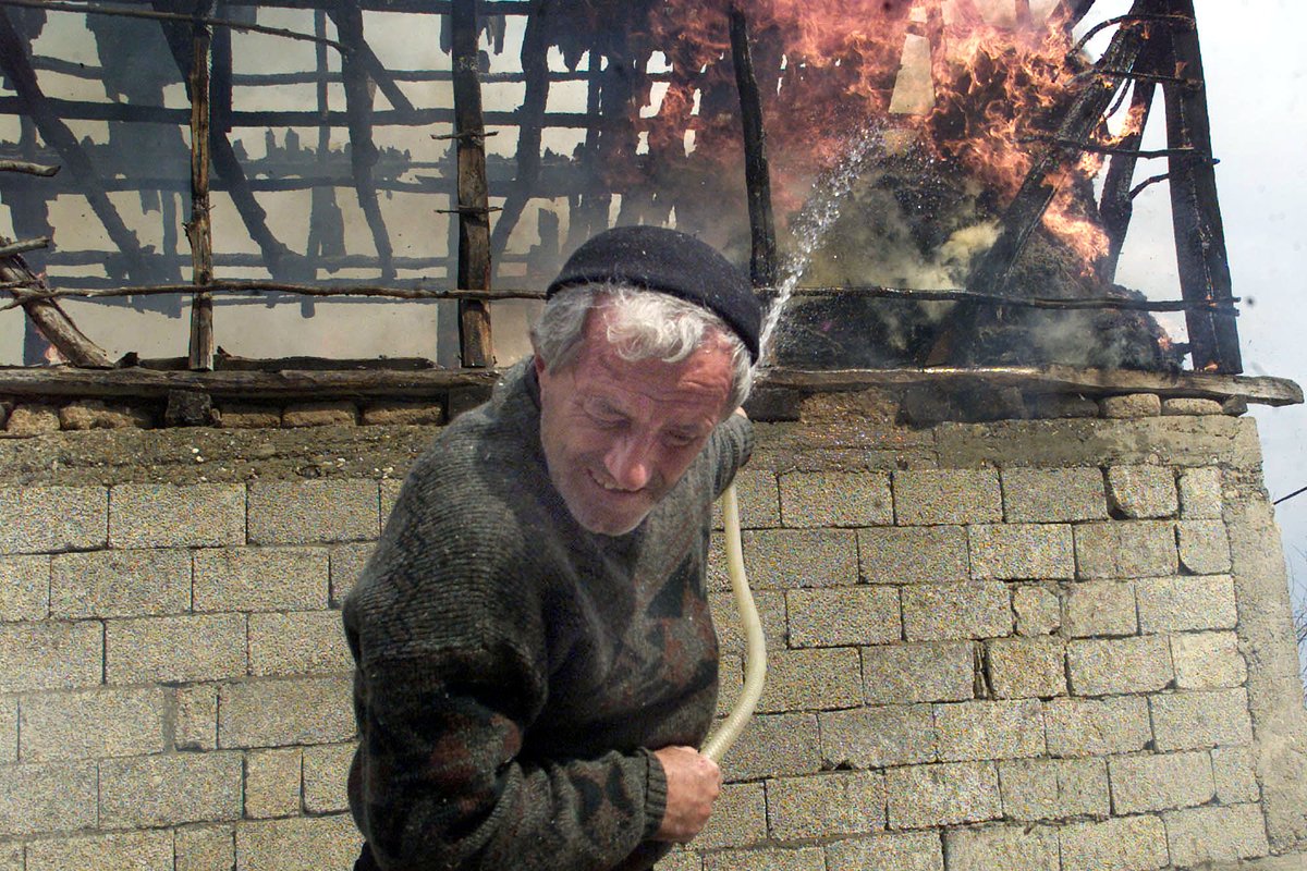Фермер — этнический албанец пытается потушить пожар, охвативший его сарай после того, как македонские солдаты вошли в контролируемую албанцами деревню Гаджре в воскресенье, 25 марта 2001 года