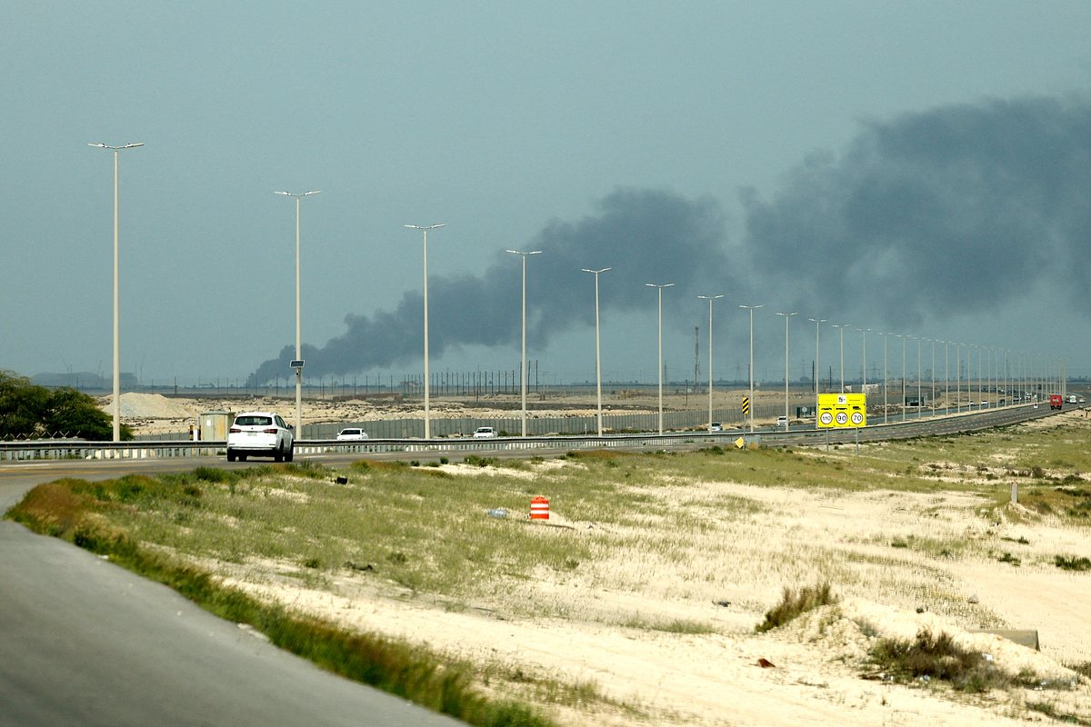 Автомобили движутся по дороге, над нефтеперерабатывающим заводом Saudi Aramco в Рас-Таннуре поднимается дым после сообщения об ударе иранского беспилотника на фоне американо-израильского конфликта с Ираном, Рас-Таннура, Саудовская Аравия, 2 марта 2026 года