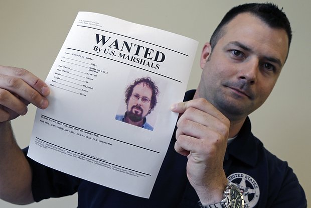 Маршал США демонстрирует плакат с объявлением о розыске Томми Томпсона в Колумбусе