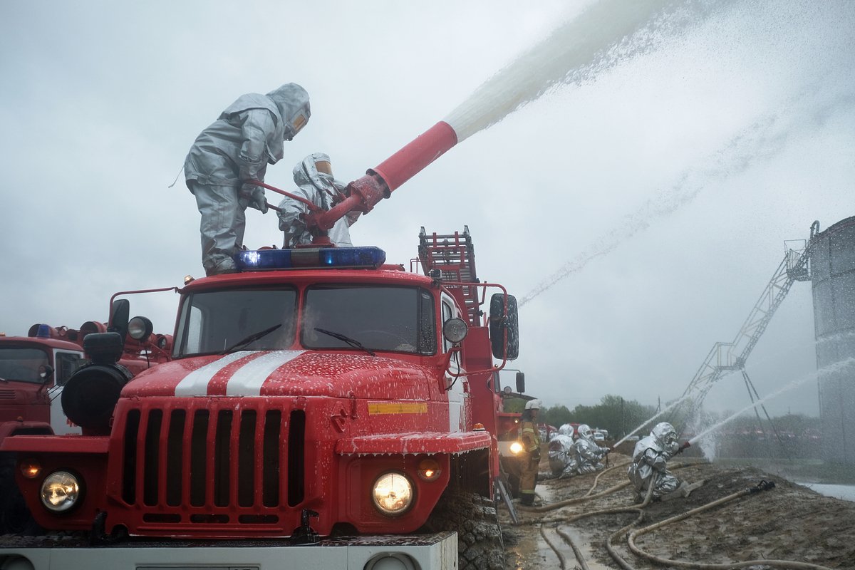 Сотрудники противопожарной службы МЧС РФ в защитных костюмах тушат пожар