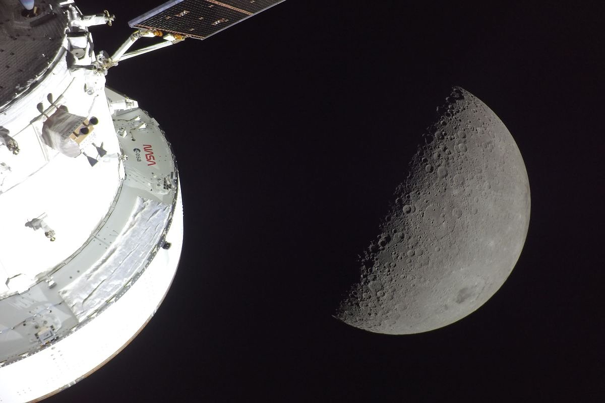 На переднем плане — корабль Orion, освещенный Солнцем, за ним — Луна. В нижней правой части спутника Земли выделяется Море Восточное с черным пятном древней лавы в центре