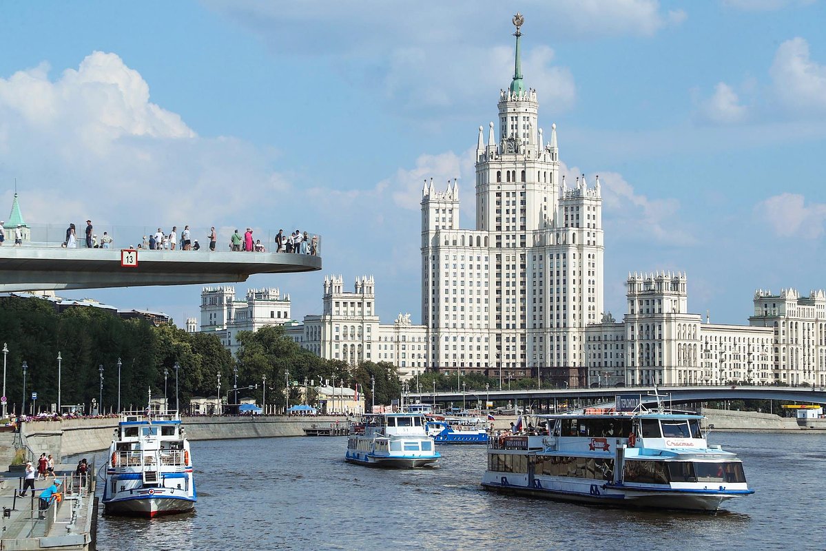 Жанровая фотография. Виды Москвы. Туристы на Парящем мосту в парке Зарядье, на фоне высотного здания на Котельнической набережной и прогулочные теплоходы на Москве-реке