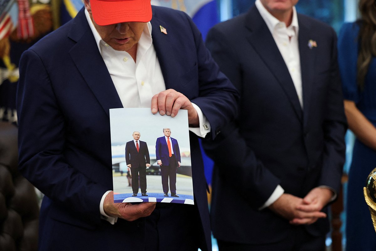 Президент США Дональд Трамп держит в руках фотографию, на которой он и президент России Владимир Путин запечатлены во время встречи в Анкоридже, 22 августа 2025 года